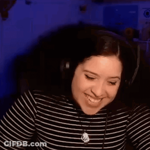 A Woman Wearing Headphones Is Laughing While Sitting In Front Of A Computer Screen . GIF