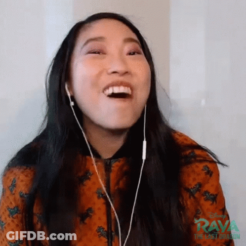 A Woman Wearing Headphones Is Laughing While Watching A Video . GIF