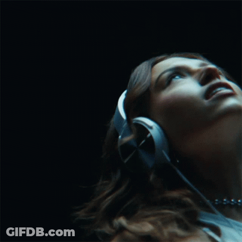 A Woman Wearing Headphones Is Listening To Music GIF