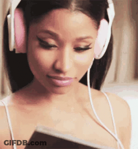 A Woman Wearing Headphones Is Listening To Music And Looking At A Book . GIF