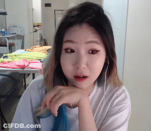 A Woman Wearing Headphones Is Looking At The Camera With Her Hand On Her Chin GIF