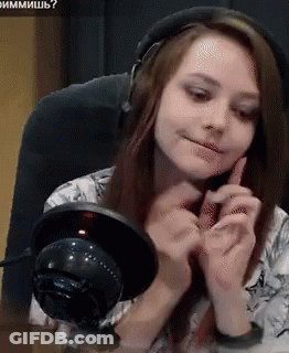 A Woman Wearing Headphones Is Sitting At A Table With A Microphone In Front Of Her GIF