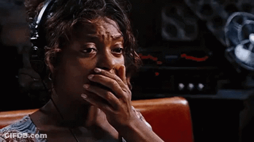 A Woman Wearing Headphones Is Sitting In A Diner And Covering Her Mouth With Her Hands . GIF