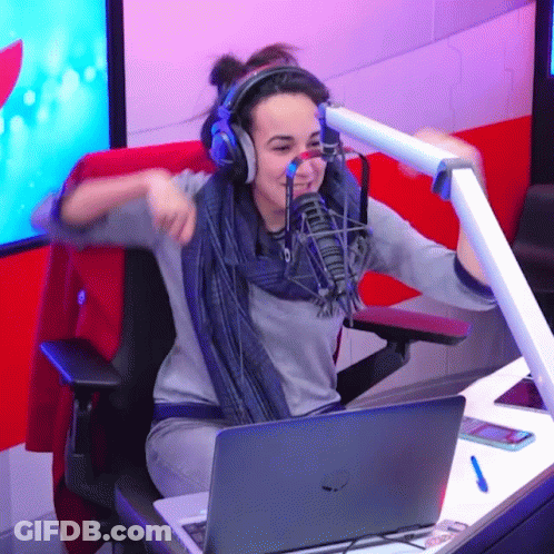A Woman Wearing Headphones Is Sitting In Front Of A Microphone And A Laptop GIF