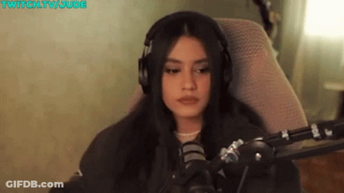 A Woman Wearing Headphones Is Sitting In Front Of A Microphone In A Chair . GIF