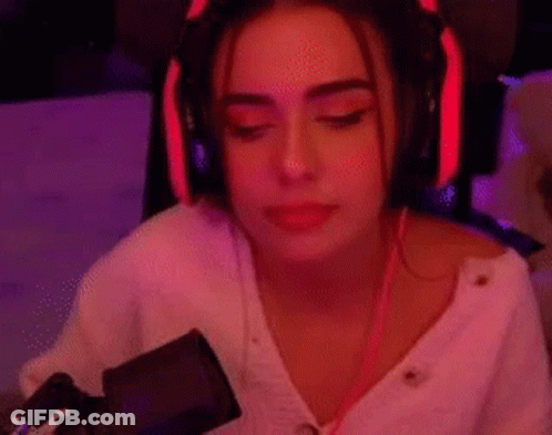 A Woman Wearing Headphones Is Sitting In Front Of A Microphone In A Room . GIF