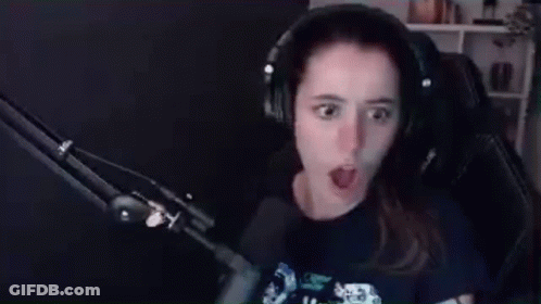 A Woman Wearing Headphones Is Sitting In Front Of A Microphone Making A Funny Face . GIF