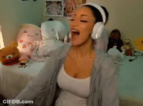 A Woman Wearing Headphones Is Sitting On A Bed In Front Of Stuffed Animals GIF