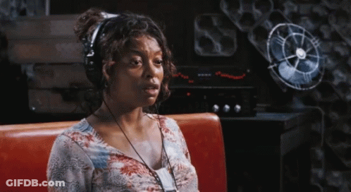 A Woman Wearing Headphones Is Sitting On A Red Bench In Front Of A Fan GIF