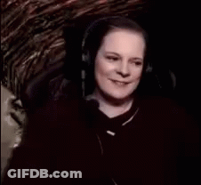 A Woman Wearing Headphones Is Smiling And Says " Witch Cackling " GIF