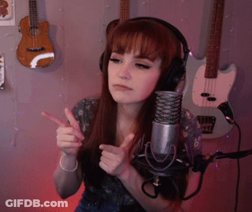 A Woman Wearing Headphones Stands In Front Of A Microphone With Guitars Behind Her GIF