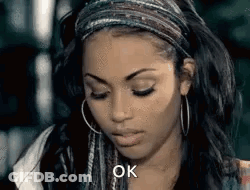 A Woman Wearing Hoop Earrings And A Headband Is Looking Down And Saying Ok . GIF