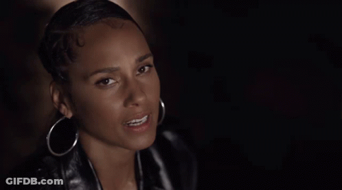 A Woman Wearing Hoop Earrings And A Leather Jacket Looks At The Camera . GIF
