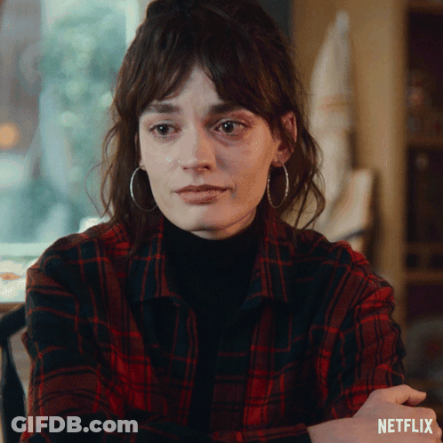 A Woman Wearing Hoop Earrings And A Plaid Shirt With Netflix Written On The Bottom Right GIF