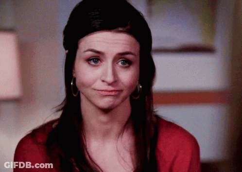 A Woman Wearing Hoop Earrings And A Red Sweater Is Making A Funny Face GIF