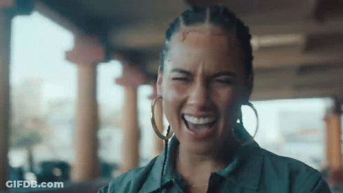 A Woman Wearing Hoop Earrings Is Laughing With Her Eyes Closed And Her Mouth Open . GIF