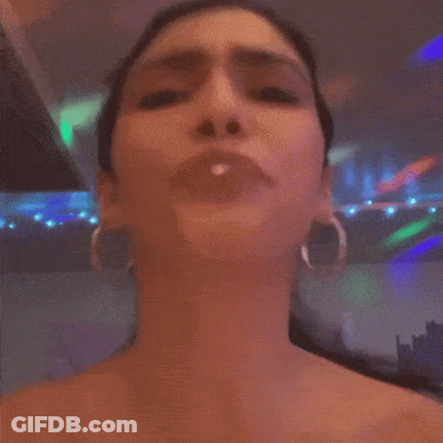 A Woman Wearing Hoop Earrings Is Making A Face GIF