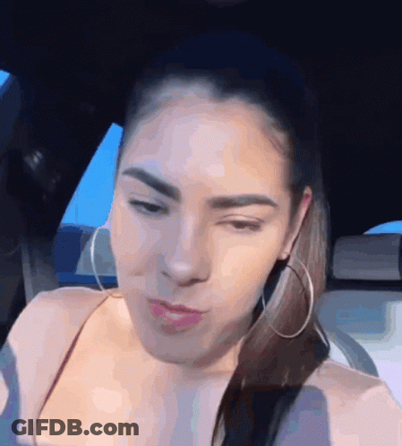A Woman Wearing Hoop Earrings Is Sitting In A Car And Making A Funny Face GIF