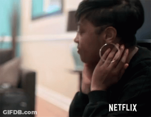 A Woman Wearing Hoop Earrings Is Sitting In Front Of A Netflix Screen . GIF
