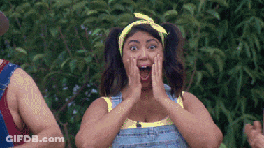 A Woman Wearing Overalls And A Yellow Headband Is Making A Surprised Face While Standing Next To A Man . GIF