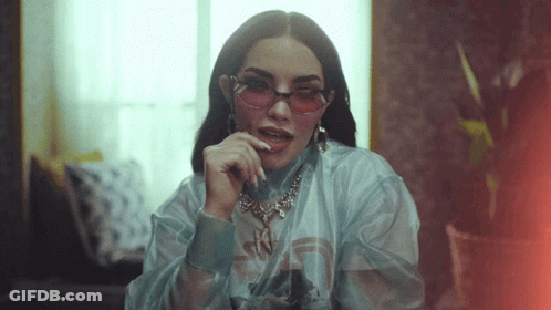 A Woman Wearing Pink Sunglasses And A Necklace With The Letter N On It GIF