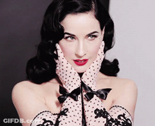 A Woman Wearing Polka Dot Gloves With A Bow On The Cuffs GIF