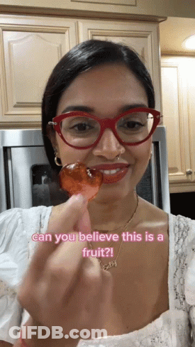 A Woman Wearing Red Glasses Is Holding A Piece Of Fruit With The Caption Can You Believe This Is A Fruit ? GIF