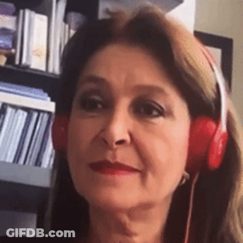 A Woman Wearing Red Headphones Is Smiling In Front Of A Bookshelf . GIF