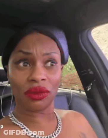 A Woman Wearing Red Lipstick And A Chain Necklace Is Sitting In A Car . GIF