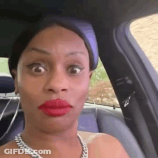 A Woman Wearing Red Lipstick And A Necklace Is Sitting In The Back Seat Of A Car Making A Funny Face . GIF