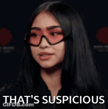 A Woman Wearing Red Sunglasses And A Black Jacket Is Saying That 'S Suspicious . GIF