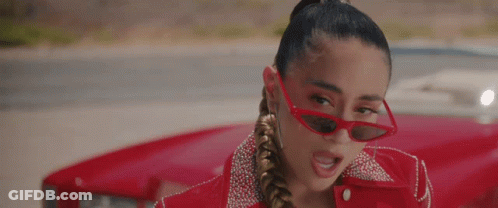 A Woman Wearing Red Sunglasses And A Red Jacket Is Standing Next To A Red Car . GIF