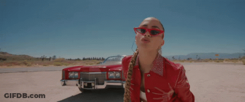 A Woman Wearing Red Sunglasses Stands In Front Of A Red Cadillac GIF