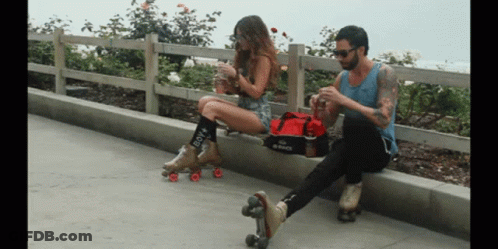 A Woman Wearing Roller Skates Sits Next To A Man GIF