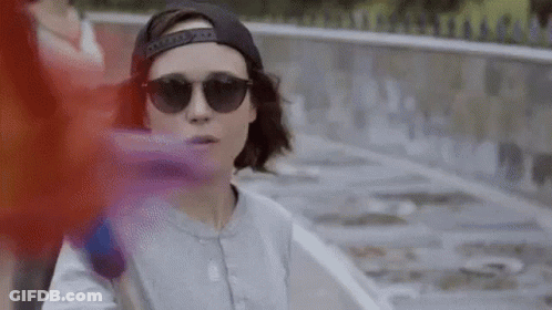 A Woman Wearing Sunglasses And A Baseball Cap Is Standing Next To A Skateboard . GIF