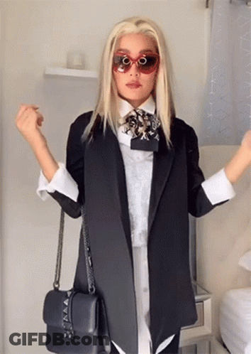 A Woman Wearing Sunglasses And A Black Jacket Holds A Black Purse . GIF