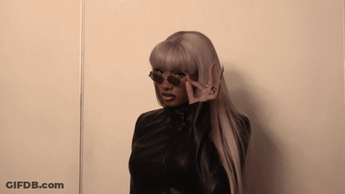 A Woman Wearing Sunglasses And A Black Jacket Making A Peace Sign GIF