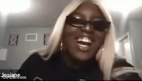 A Woman Wearing Sunglasses And A Black Shirt Is Smiling While Looking At The Camera . GIF