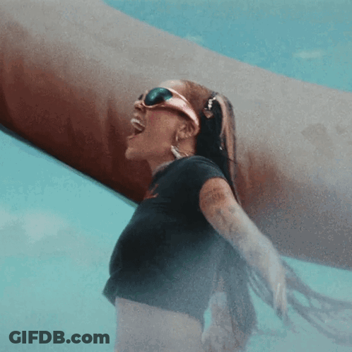 A Woman Wearing Sunglasses And A Black Shirt Stands In A Pool GIF