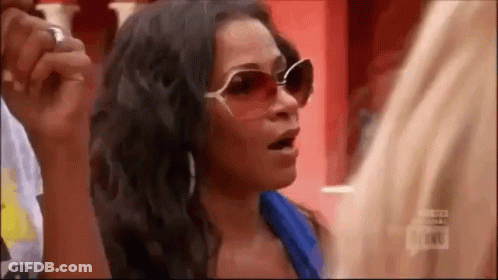 A Woman Wearing Sunglasses And A Blue Shirt Is Talking To A Man . GIF