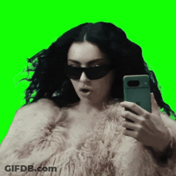 A Woman Wearing Sunglasses And A Fur Coat Is Taking A Selfie GIF