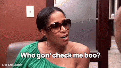 A Woman Wearing Sunglasses And A Green Dress Is Sitting In A Chair And Talking To Another Woman . GIF