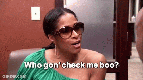 A Woman Wearing Sunglasses And A Green Dress Is Sitting In A Chair And Talking To Another Woman . GIF