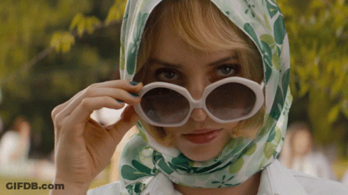 A Woman Wearing Sunglasses And A Head Scarf Looks At The Camera GIF