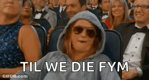 A Woman Wearing Sunglasses And A Hoodie Is Sitting In A Crowd Of People With The Words Til We Die Fym Behind Her . GIF