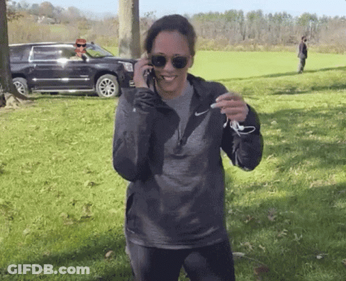 A Woman Wearing Sunglasses And A Nike Sweatshirt Talks On A Cell Phone GIF