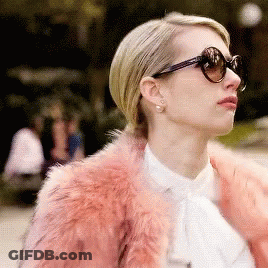 A Woman Wearing Sunglasses And A Pink Fur Coat Looks To The Side GIF