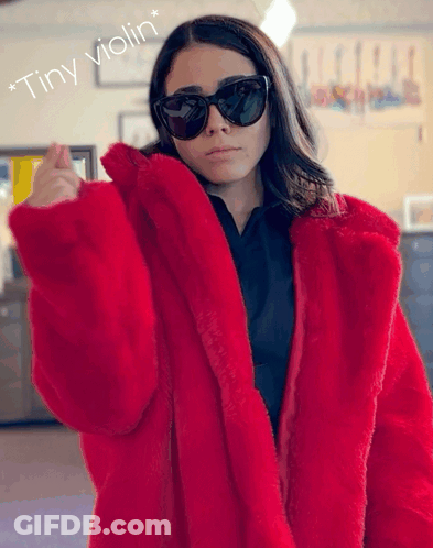 A Woman Wearing Sunglasses And A Red Fur Coat With The Words " Tiny Violin " Below Her GIF