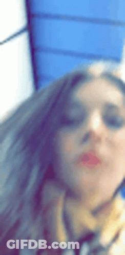 A Woman Wearing Sunglasses And A Scarf Is Taking A Picture Of Herself . GIF