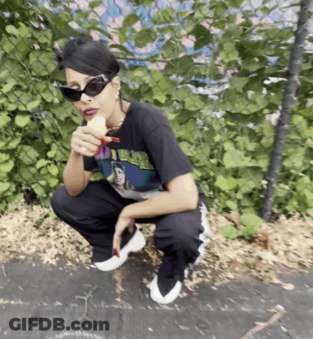 A Woman Wearing Sunglasses And A Shirt That Says I 'M Black Is Eating A Banana GIF